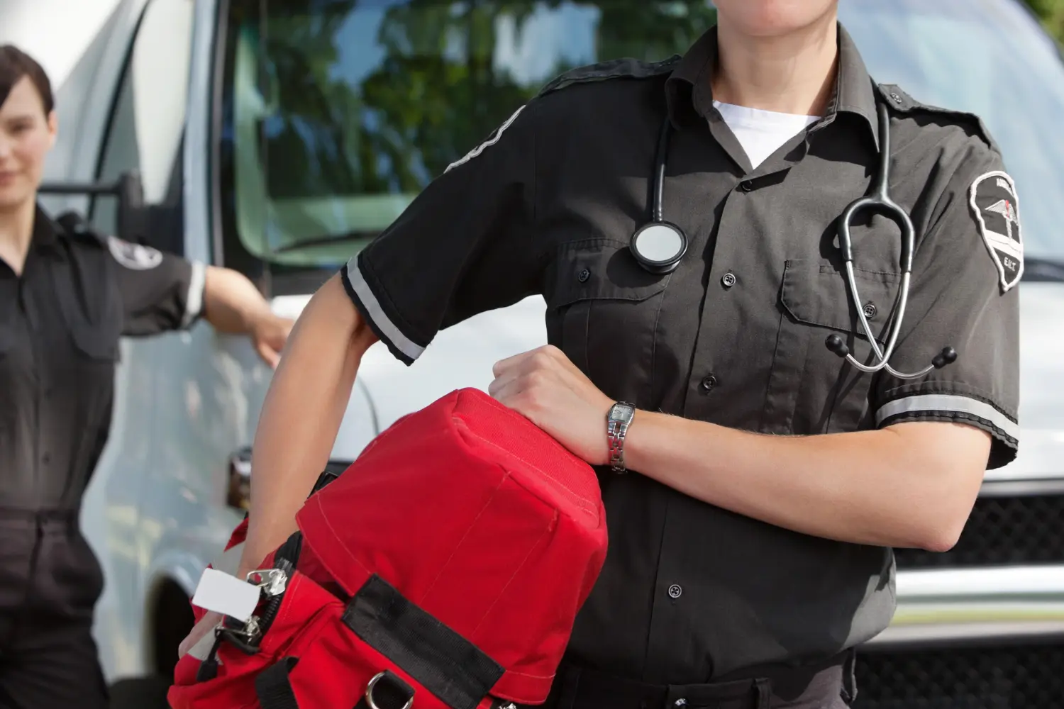 a first responder holding a bag in front of the ambulance