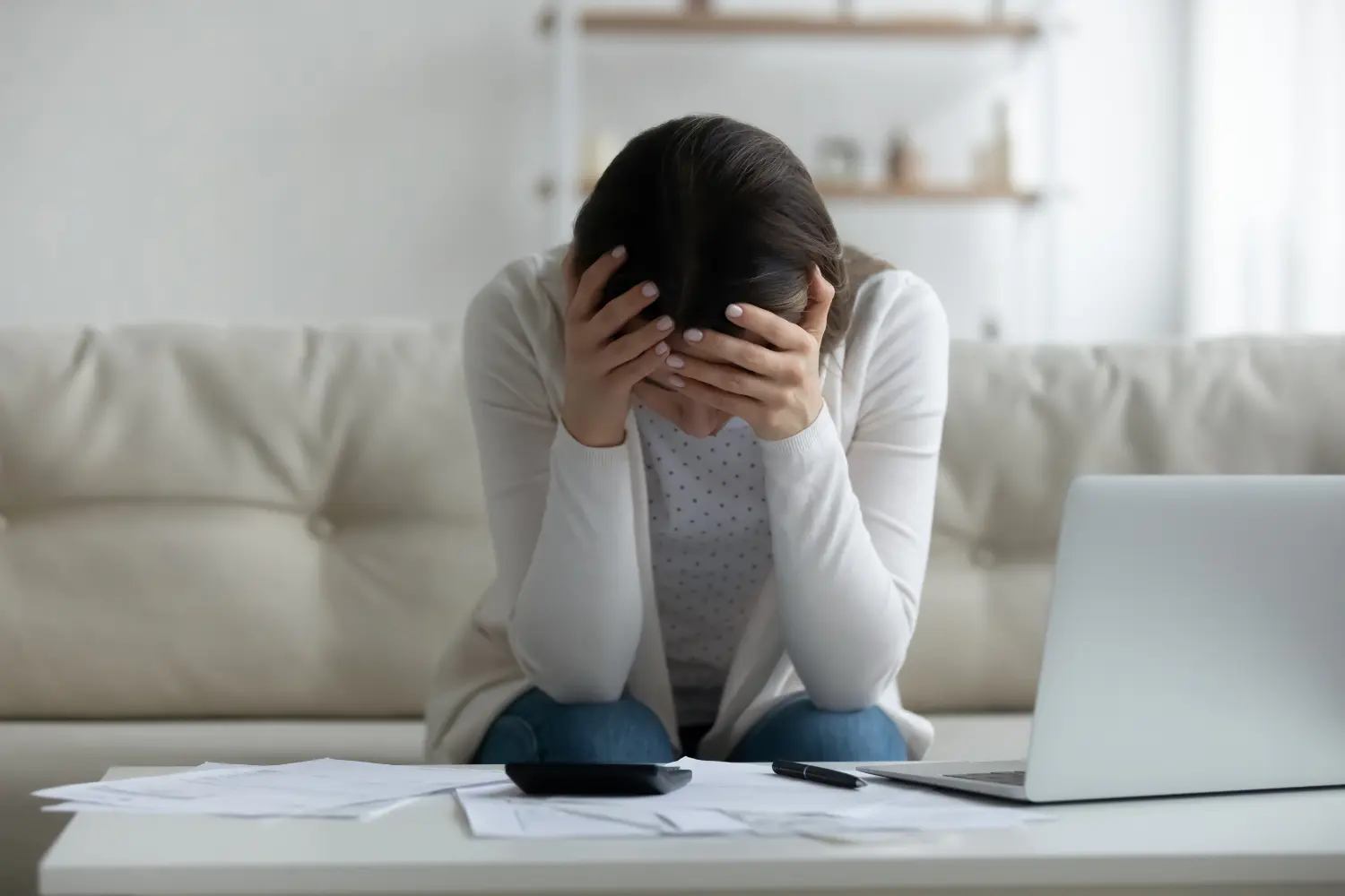 a woman feeling stressed with finances holding her head in her hands