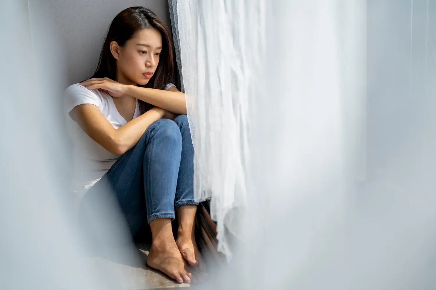 a woman sitting in the corner of her room depressed