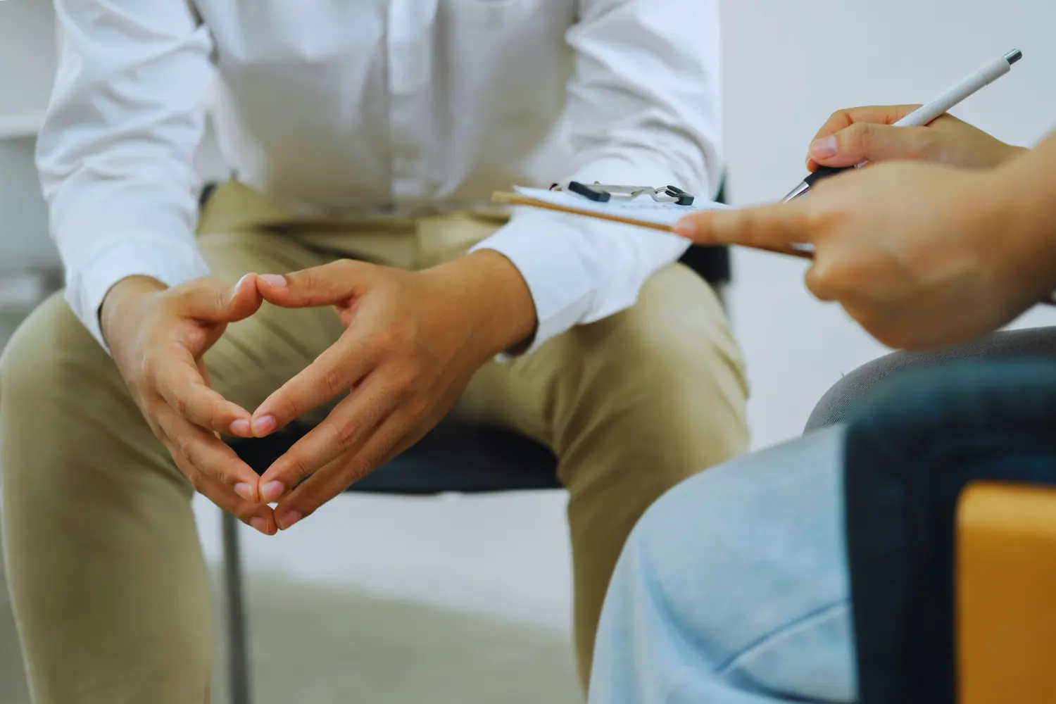 close up of the hands of a patient as their therapist writes notes