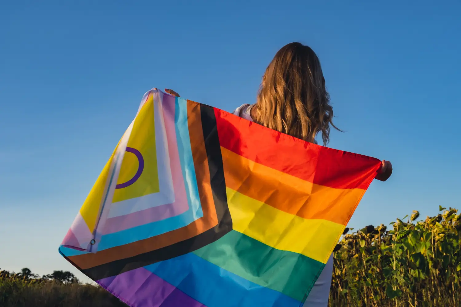 closeup of a LGBTQIA plus flag being held in a field