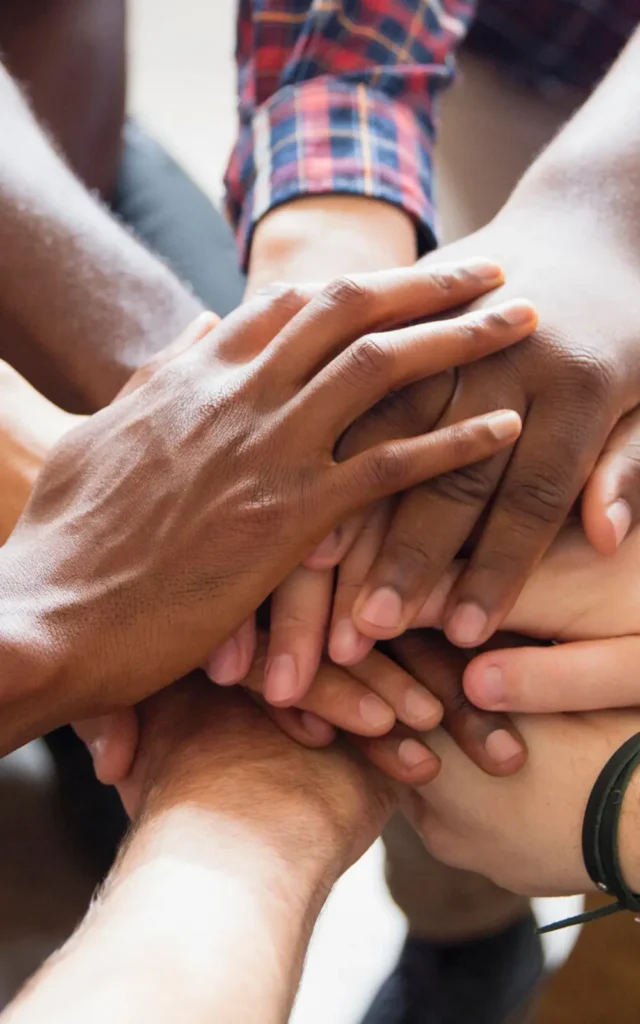 diversity and inclusion - a group reaches out their hands to one another in support of diversity vertical