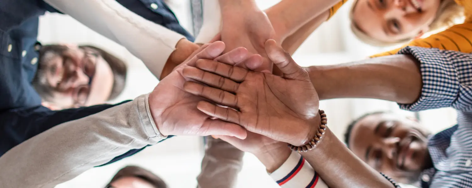 team members layering hands together