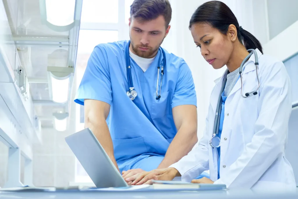 two medical professionals inputting medical research into a laptop