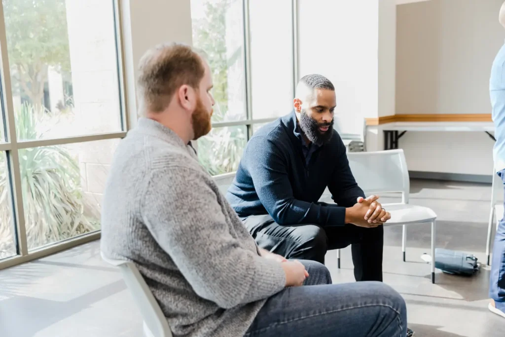 two men talking in a group therapy sessions