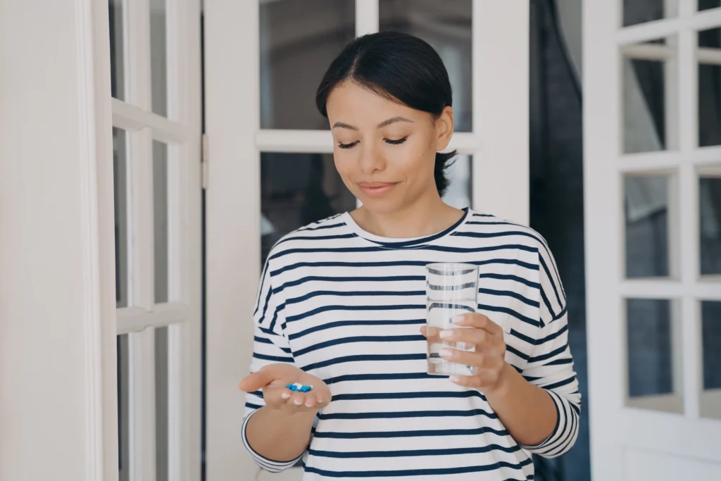 Can You Take Ibuprofen With Gabapentin? A woman holding pills her one hand and a glass of water in the other.