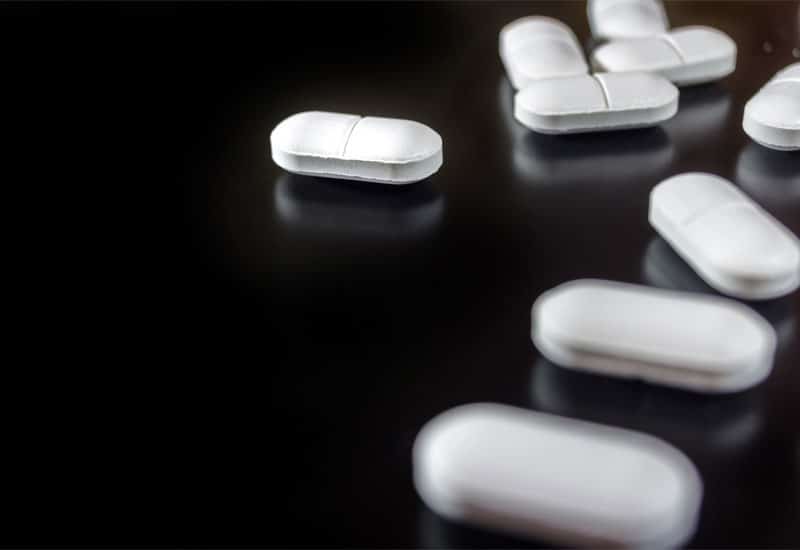 Gabapentin Abuse: An image of white pills on a black surface