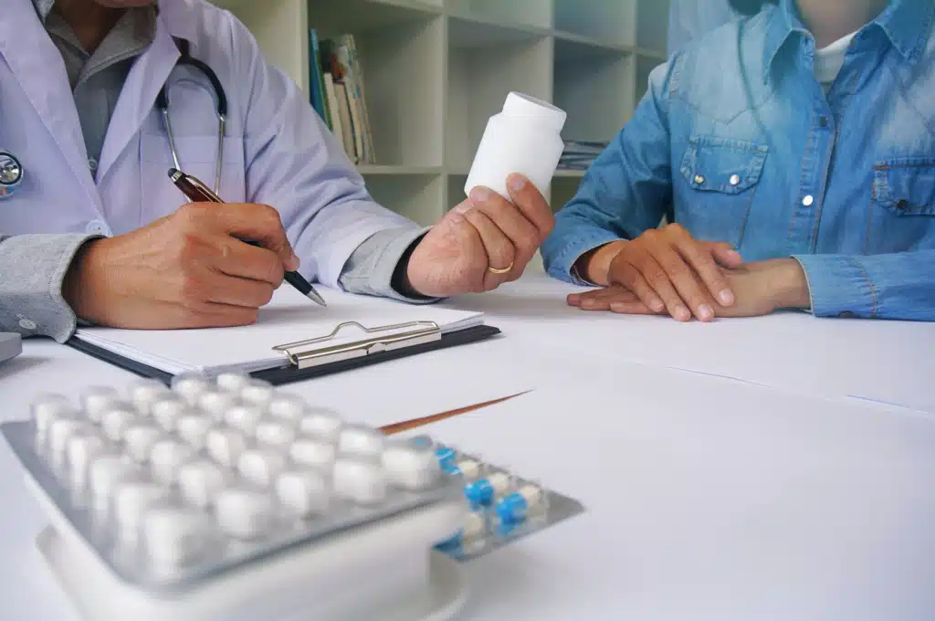 Ambien withdrawal. Doctor discussing medication with a patient, holding a pill bottle during a medical consultation.
