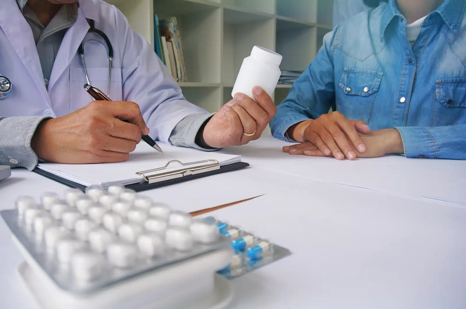 Ambien withdrawal. Doctor discussing medication with a patient, holding a pill bottle during a medical consultation.