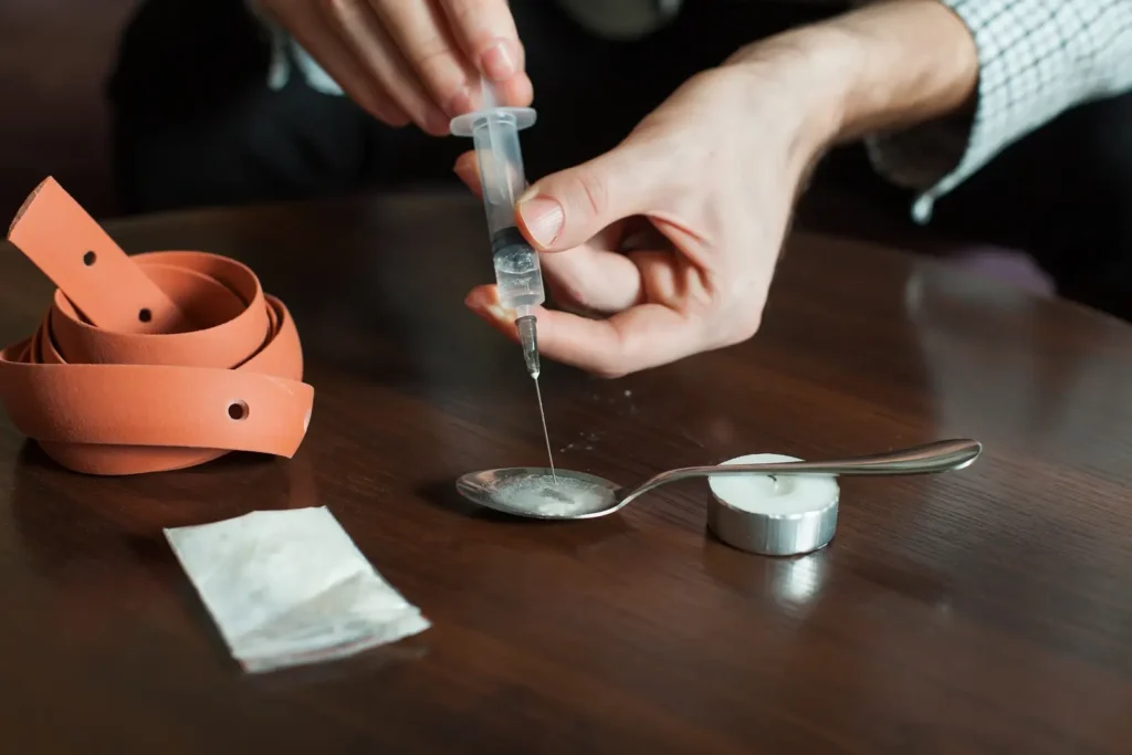 Cotton fever. Drug addict man gathers a dose of heroin with syringe through cotton